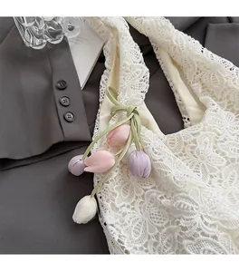 Détail du sac cabas en dentelle ivoire avec texture crochet et breloque fleur de tulipe