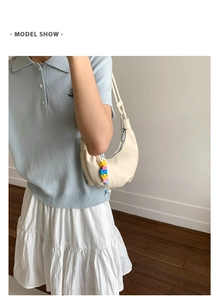Shoulder view of a cream hobo bag with colorful letter bead charms and leather texture