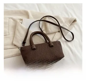 Gros plan sur le sac à main marron foncé tressé avec des détails de boules décoratives