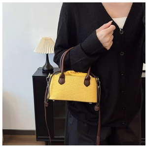 Close-up of vibrant yellow straw bag with brown leather handles and drawstring closure