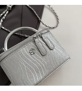 Dettaglio della borsa a scatola argento con glitter zebrati e logo floreale in metallo