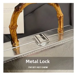 Detail of silver embossed leather bag with bamboo handle and metal press-lock closure