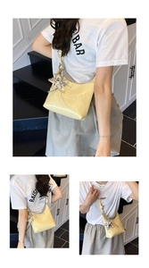Détail du sac à bandoulière en cuir verni jaune clair avec un charme d'étoile de mer