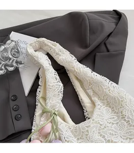 Détail de la texture en dentelle blanche du sac avec charms tulipes et nœud vert