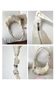 Detail view of cream crescent bag featuring knotted straps and colorful bead charms