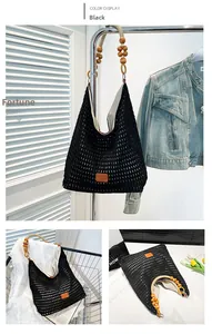 Detail of black woven mesh tote bag with wooden bead handle and leather patch detail