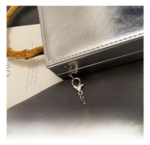Macro detail of the silver textured PU leather handbag with bamboo handle and metal chain