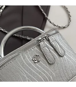 Dettaglio borsa a scatola argento glitter con doppia zip e stemma floreale metallico