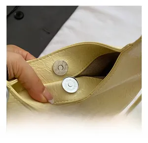 Détail du sac plissé jaune avec fermoir magnétique rond en argent et doublure brune
