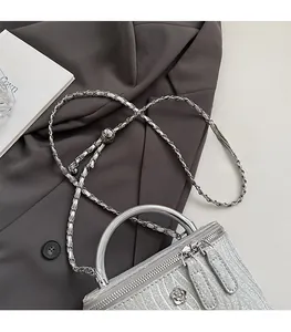 Dettaglio borsa a scatola glitter argento con manico metallico e zip a camelia