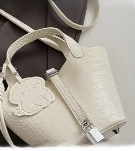 Detail of off-white crocodile embossed handbag with silver metal lock and cloud charm