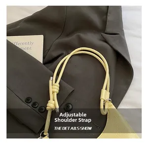 Gros plan sur la bandoulière réglable à nœuds d'un sac à main jaune plissé élégant