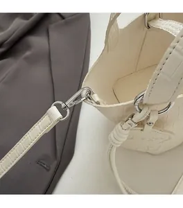 Detail of silver hardware and crocodile pattern on a cream mini crossbody handbag