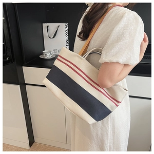 Detailed shot of large canvas tote bag with red and blue stripes and leather straps