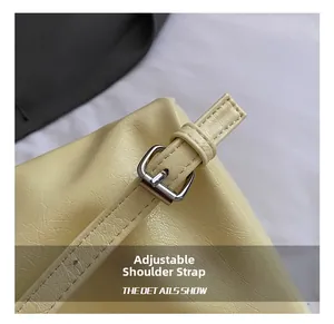 Detail view of light yellow bucket bag featuring adjustable strap and silver metal buckle