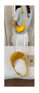 Close-up of a bright yellow croissant bag with unique knotted shoulder strap detail