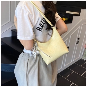 Détail du sac hobo plissé jaune avec un grand pendentif étoile en paillettes argentées