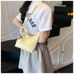 Détail du sac seau hobo plissé crème avec breloque étoile argentée et nœud décoratif
