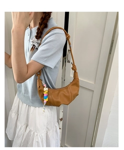 Detail of brown leather croissant bag with colorful letter bead charm and knotted strap