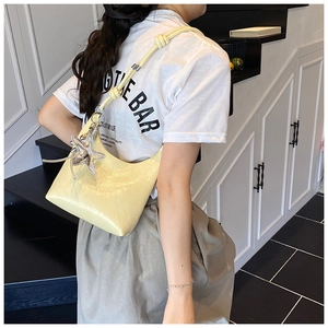 Détail du sac demi-lune jaune clair avec un pendentif étoile de mer argenté et bandoulière nouée