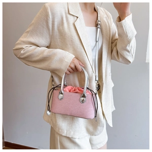 Detail of pink woven bucket bag featuring metallic silver handle and drawstring lining