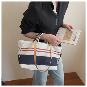 Detail of nautical stripe canvas tote bag with brown leather straps and drawstring closure