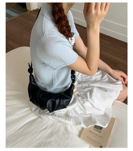 Detailed view of a black pleated crescent underarm bag in a minimalist lifestyle setting
