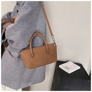 Close-up of brown woven texture handbag with silver zippers and cylindrical dual handles