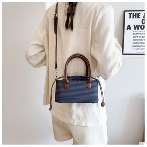 Blue straw woven tote bag with brown leather handles and adjustable shoulder strap
