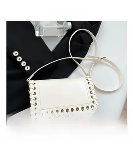 Close-up of ivory crossbody bag with woven leather rope trim and metal eyelets detail