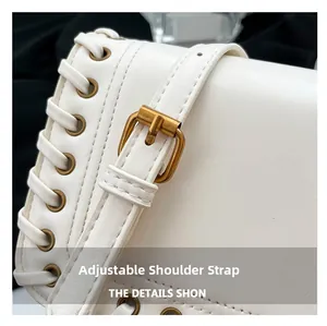 Detail view of white leather bag with adjustable strap and golden metal buckle