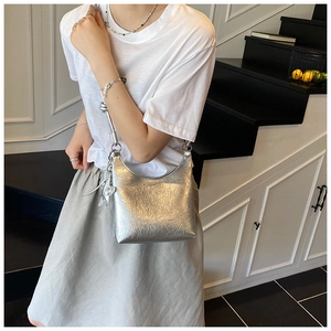 Détail d'un sac à bandoulière argenté métallisé avec texture plissée et étoile