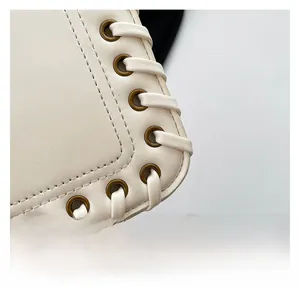 Macro detail of ivory leather bag with braided edge craftsmanship and bronze eyelets