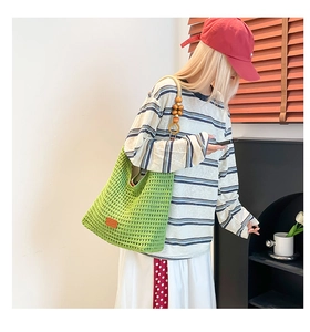 Detail of green handmade crochet tote bag featuring wooden bead strap and mesh texture