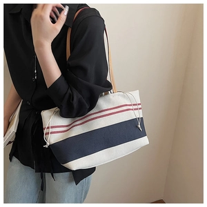 Detail der nautisch gestreiften Canvas-Tasche mit Kordelzug und Leder-Schultergurten