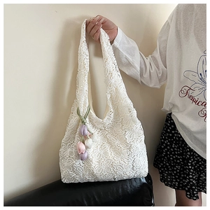 Détail du sac cabas en dentelle florale blanche avec motifs évidés et charms de tulipes