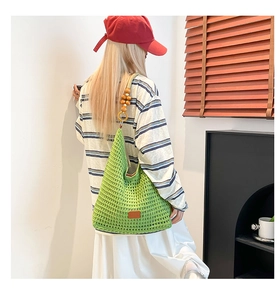 Detail of green knit tote bag with wooden bead straps and hollow weave texture