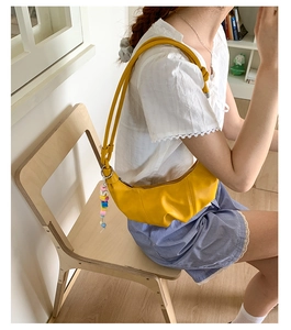 Detail of yellow crescent hobo bag featuring soft pleats and colorful beaded charm