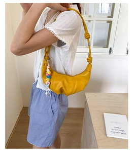 Detail of ginger yellow crescent bag with knotted strap and colorful letter bead charm