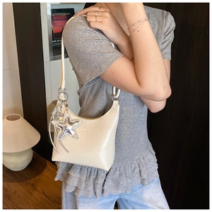 Détail du sac rétro crème avec finition en cuir brillant et breloque étoile argentée
