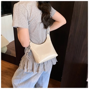Vue détaillée de la texture en cuir verni blanc crème et du charme métallique de ce sac