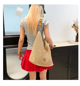 Detail of hollow knit tote bag featuring wooden bead shoulder straps and mesh texture