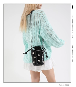 Détail du sac seau noir verni avec clous argentés et poignée anneau sur le mannequin
