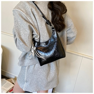 Détail d'un sac hobo en cuir verni noir froissé avec un pendentif en forme d'étoile argentée