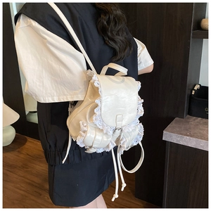 Detail view of a white PU leather backpack with vintage lace trim and buckle closure