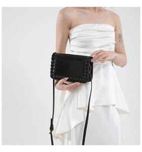 Detailed view of black patent leather crossbody bag with metal eyelet and lace-up edges