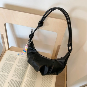 Detail of a black pleated crescent bag with colorful letter beads on a wooden chair