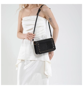 Detail of black woven shoulder bag with gold hardware worn on a white dress