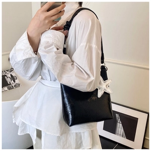 Gros plan du sac seau en cuir verni noir avec un accessoire charm étoile argenté brillant