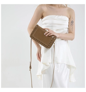 Detail of dark brown woven edge envelope bag featuring premium leather texture and stitching